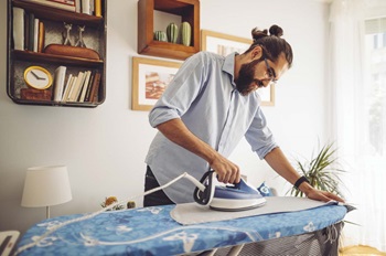 homem a passar a ferro em casa